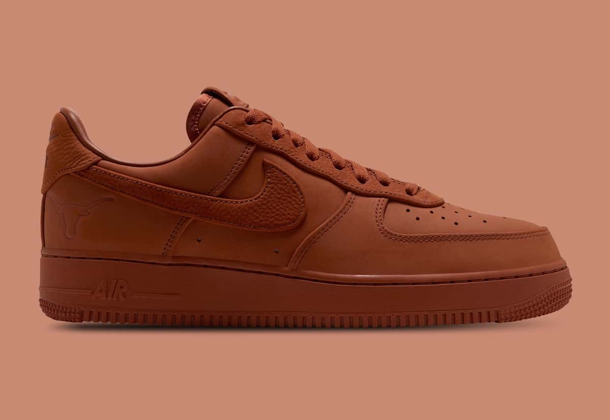 Nike Air Force 1 Low Luxe de la Universidad de Texas de perfil lateral sobre fondo terracota, entero en naranja tostado de la capellada a la suela, con el Swoosh de textura granulada y la cabeza de longhorn grabada en el talón