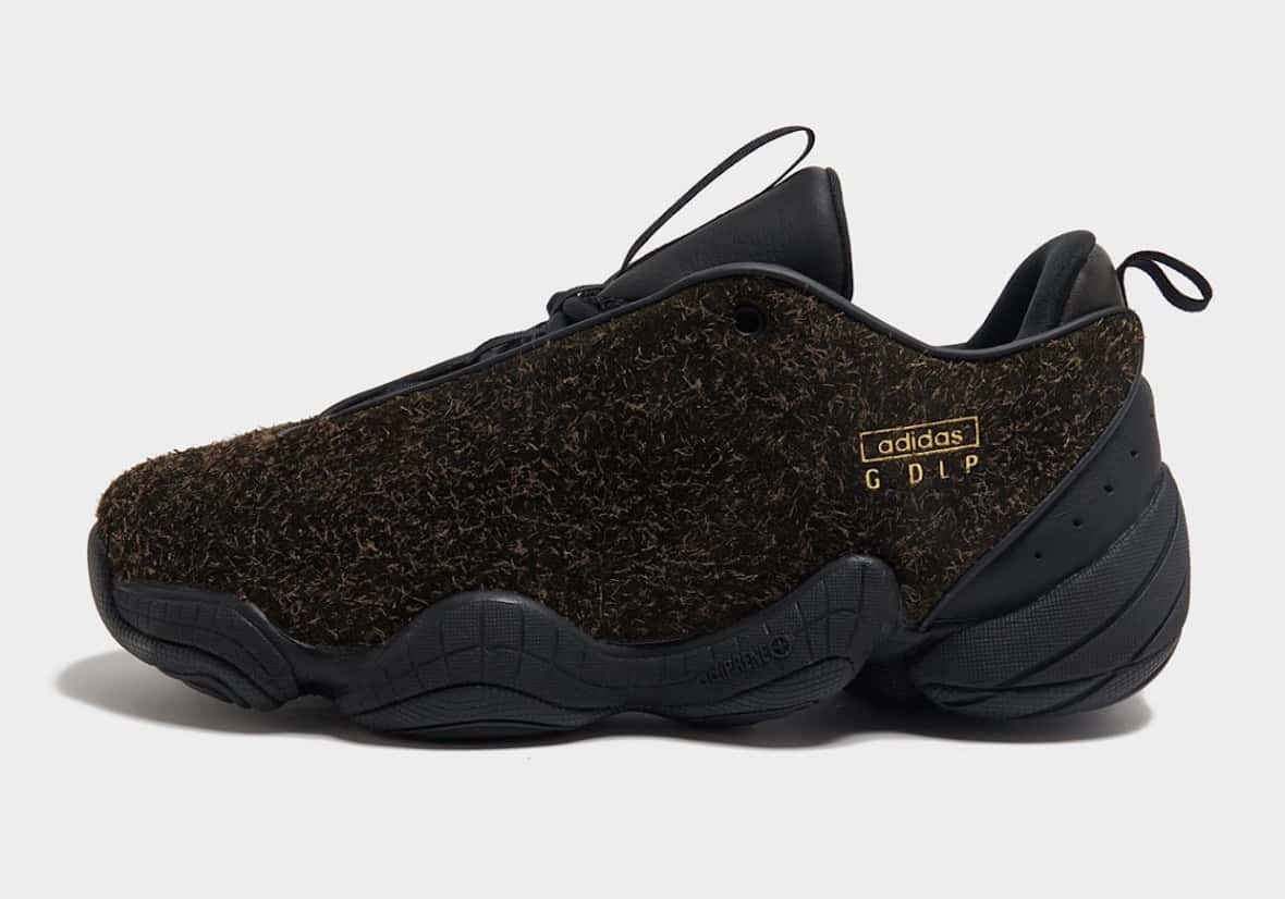 Guadalupe x adidas Intimidation de perfil sobre fondo gris claro, con el upper cubierto de gamuza de pelo largo marrón oscuro, la base negra ondulada, la tira del talón y el logo adidas GDLP en dorado