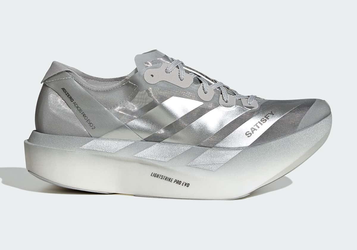 Satisfy x adidas Adios Pro Evo 2 plateada de perfil, con capellada translúcida, las tres tiras plateadas y la palabra SATISFY en el lateral